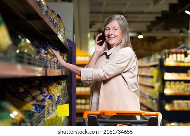 An Older Woman Talks On The Phone And Goes Shopping In The Grocery Store