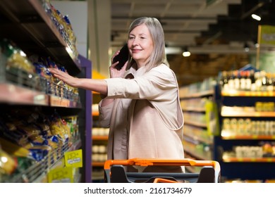 An Older Woman Talks On The Phone And Goes Shopping In The Grocery Store