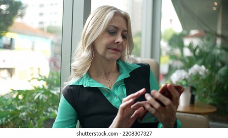 Older Woman Using Phone At Coffee Shop. Senior Businesswoman Typing Message On Smartphone At Cafe Place. Female Executive Looking At Cellphone