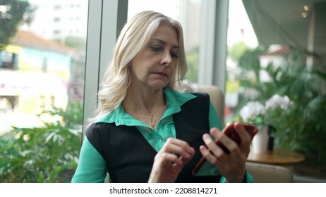 Older Woman Using Phone At Coffee Shop. Senior Businesswoman Typing Message On Smartphone At Cafe Place. Female Executive Looking At Cellphone