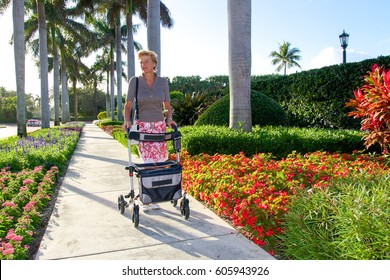 Older Woman Walking With A Walker In Palm Beach, FL On A Sunny Day.