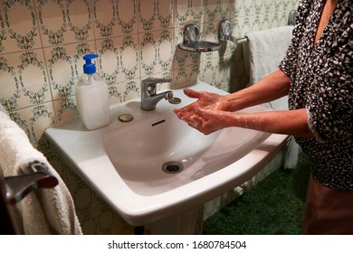 Older Woman Washing Her Hands With Soap And Water In The Sink To Maintain Hygiene