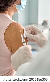 Older Woman Wearing Face Mask Getting Vaccination Injection. Doctor Vaccinating Old Patient. Vaccine And Senior People Inoculation, Elderly Immunity For Covid Prevention Immunization. Vertical Closeup