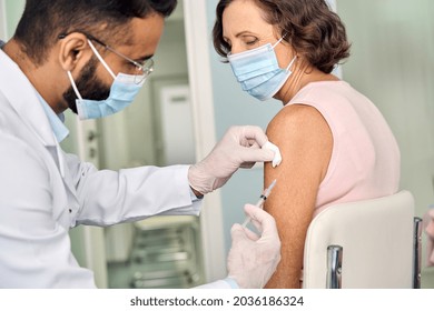 Older Woman Wearing Face Mask Getting Vaccination Injection. Indian Doctor Vaccinating Old Patient. Vaccine And Senior People Inoculation, Elderly Immunity For Covid Prevention Immunization Concept.