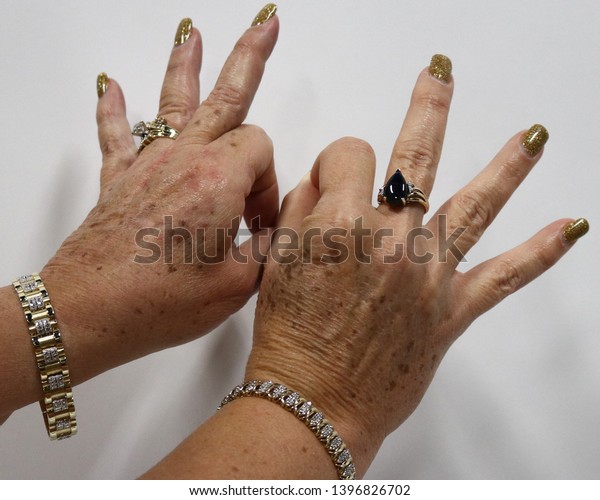 An older woman wearing jewelry signing the\
word \