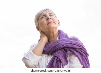  Older Woman With White Hair, White Shirt An Purple Scarf With Neck Pain