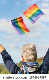 Older Woman With White Hair Waving Two Rainbow Gay Pride Flags. Senior Person Of The Lgbt Collective. Pride Day.