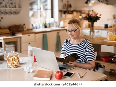 Older woman working from homeoffice. The retiree earning extra money during retirement. Woman paying bills online. - Powered by Shutterstock