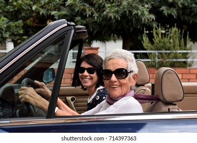 An Older Woman And A Young Woman Driving A Convertible