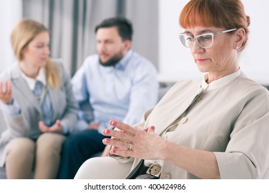 Older Worried Psychologist And Young Married Couple Fighting During Session