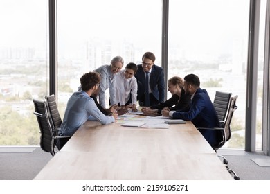 Older and young teammates gathered in modern office boardroom at corporate briefing, share solutions and creative ideas, discuss collaborative project feel satisfied. Teamwork, seminar event concept