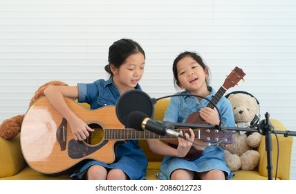 Older and Younger Sisters Kids Singing Song While Playing Guitar and Ukulele Together