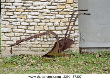 the oldest known agricultural implement used for the simplest plowing. old metal horse plow. Vintage horse plow. Old lister by a stone wall. historical iron council