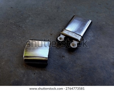 An old-fashioned chrome lighter with two round sparking teeth. isolated on cement floor