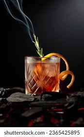 Old-fashioned cocktail with ice, orange peel, and rosemary. Whiskey with a burning twig of rosemary on a dark background. - Shutterstock ID 2365425895