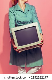 Old-fashioned Style. Colorful Image Of Woman Holding Retro Computer Monitor Isolated Over Light Pink Background. Concept Of Pop Art, Vintage Things, Mix Old And Modernity. Copy Space For Ad