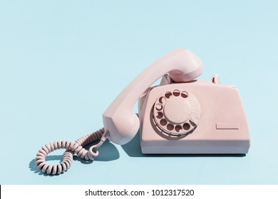Oldschool pink telephone on a blue background. Telecommunication. Vintage objects.