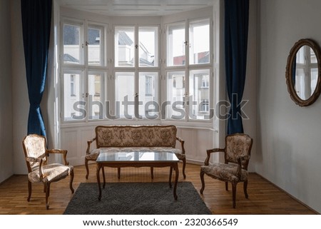 Old-world European luxury interior furniture with a matching sofa and two chairs in a room with brightly lit windows