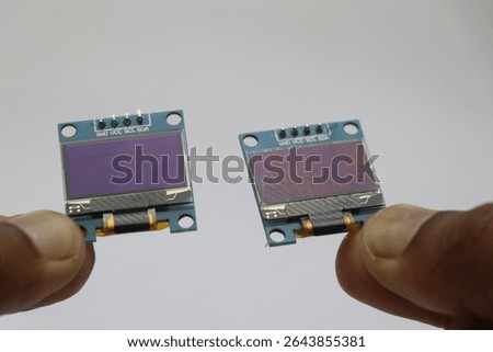 OLED screen with working and broken display held in the hand side by side on a white background