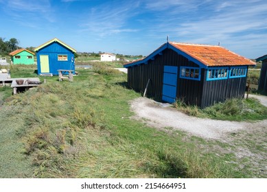 Oleron Island, Charente Maritime, France. An oyster farming site and multi-coloured fisherman sheds in tidal salt marsh in summer
