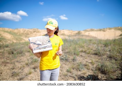 Oleshky Sand, Ukraine - June 15, 2021: Summer Vacation In Ukraine. Excursion For Tourists In Desert. Yong Lady Is Showing Picture Of Jumping Mouse. Dressed In Yellow Uniform