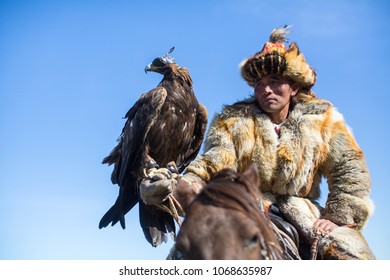 OLGIY, MONGOLIA - SEP 30, 2017: Kazakh Golden Eagle Hunter at traditional clothing, with a golden eagle on his arm during annual national competition with birds of prey Berkutchi of West Mongolia. - Shutterstock ID 1068635987