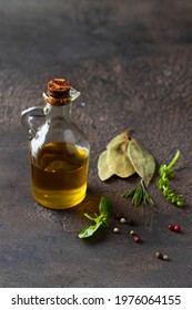 Olive Oil  Bottle  And Different Spices, Pepper, Allspice Peppercorns And Bay Leaf On Concrete Background. Condiment And Seasoning Concept.