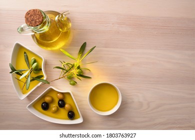 Olive Oil In Containers With Olives On Wooden Kitchen Bench. Top View.