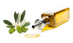 Olive Oil Dripping From A Glass Bottle And A Twig Of Olive Tree With Green Olives Isolated On White Background.

