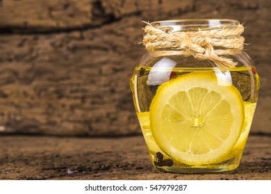 Olive oil flavored with lemon and red beans and black pepper in a glass jar on old wooden background - Powered by Shutterstock