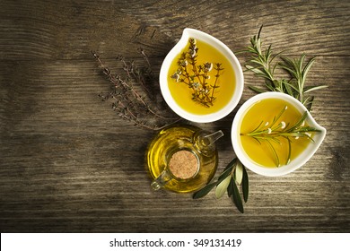 Olive Oil With Fresh Herbs On Wooden Background.