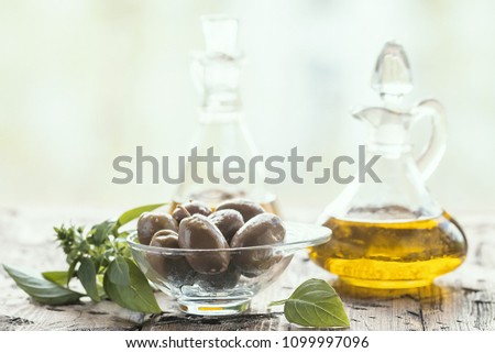 olive oil in glass bottle and olives over old wooden table