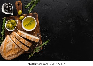 Olive oil and olives in bowls, sliced bread and rosemary on cutting board over concrete background, top view, copy space - Powered by Shutterstock