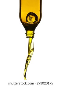 Olive oil pouring from glass bottle against white background