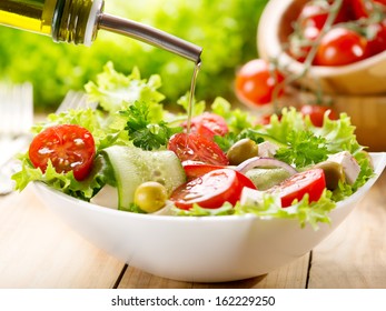 olive oil pouring into bowl of salad
