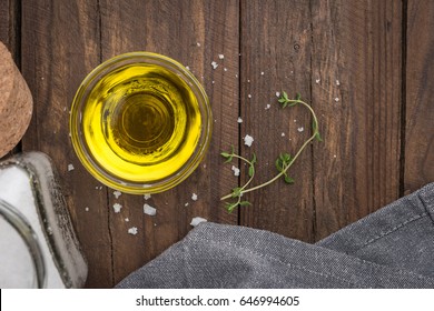 Olive oil with thyme and salt flower on wooden background. Top view