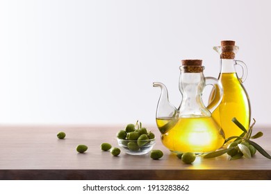 Olive Oil In Two Glass Containers And Harvest Olives On The Wooden Bench White Isolated Background. Front View. Horizontal Composition.