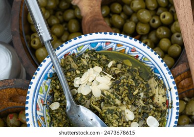 Olive tapenade, savory green mixed olives, capers, parsley, garlic, lemon zest. Traditional Mediterranean street food with toasted bread, bruschetta, antipasto garnished with sliced almonds - Powered by Shutterstock