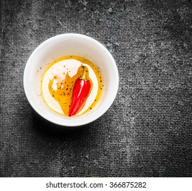 Olives Oil And Red Chili Pepper In Bowl On Dark Rustic Background, Top View