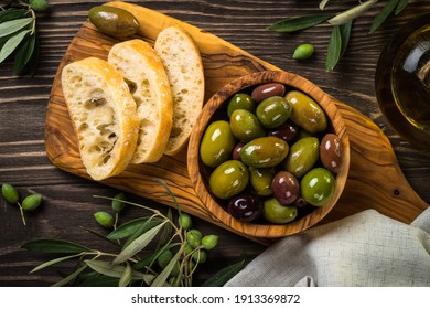 Olives, olive oil and ciabatta bread on dark wooden table. Top view. - Powered by Shutterstock