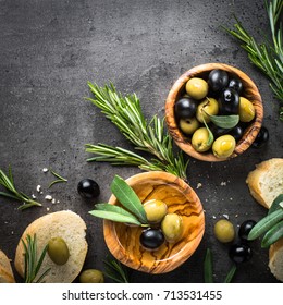 Olives, Olive Oil Rosemary And Bread On Black Slate Background. Top View  Copy Space. Square.