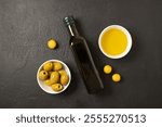 Olives and olive oil in white bowl with bottle of olive oil on dark background. Mockup for package. Copy space. High quality photo