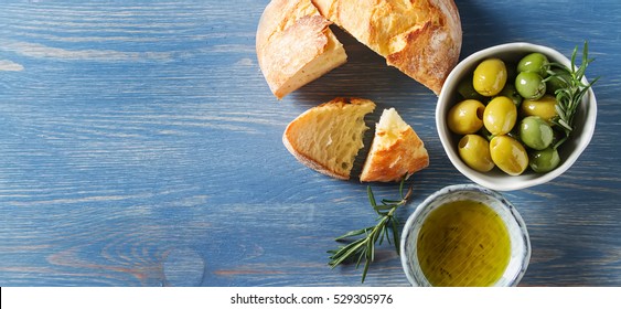 Olivier Oil With Fresh Herbs And Bread. Blue Background. Italian And Greek National Food