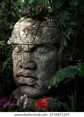 Olmec sculpture carved from stone. Mayan symbol - Big stone head statue in a jungle