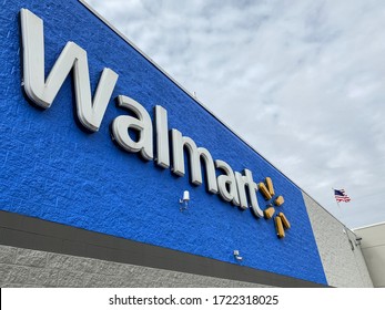 OLNEY, ILLINOIS - 02/12/2020 - Walmart logo and name on building with blue background. Store entrance with american flag waving in the wind. 