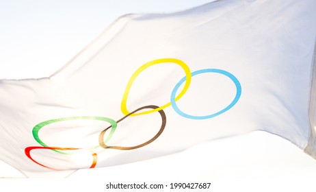 The Olympic flag flutters in the wind against the background of the sky and the sun in close-up. The symbol of the Olympic Sports Games, fans of competitions . Kaluga, Russia, May 20, 2021 