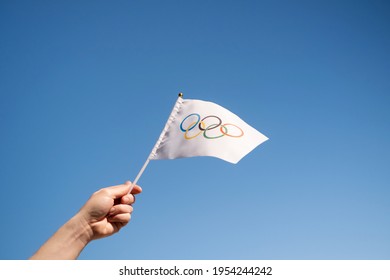 The Olympic flag, small in hand, flutters against the backdrop of a blue cloudless sky. Concept for Winter and Summer Olympic Games, 2021, 2022. Copyspace. - Moscow, April 12, 2021.