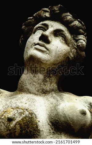 Olympic goddess of love in antique mythology Aphrodite (Venus) on black background. Fragment of ancient statue. Vertical image.