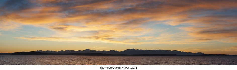Olympic Mountains Panorama. Panoramic view of the Olympic Mountain range seen from the Seattle waterfront during a dramatic springtime sunset.