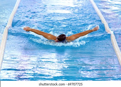 Olympic swimmer during butterfly stroke training in indoor swimming pool.